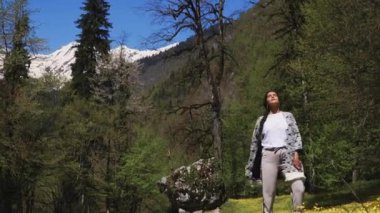 Kadın yalnız gündüzleri güneşli çayır çiçeklerle yakınındaki ormanlık üzerinde yürüyor