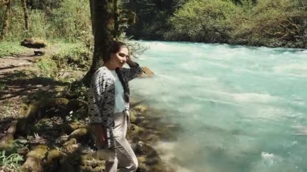 Κορίτσι με σκούρα μαλλιά αναπαύεται στην σκιά των ψηλών δέντρων το καλοκαίρι κοντά σε Ποταμός — Αρχείο Βίντεο