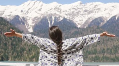 kollarını yukarı yüksek karla kaplı dağ önünde genç bir kadın yükseltir