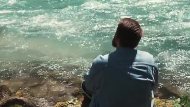 Szomorú ember ül erdő területén folyó tanácskozás víztől — Stock videók