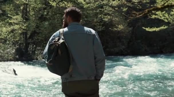 Der Mensch beobachtet die Natur im Wald, mit dem Rücken zur Kamera und dem Gesicht zum Fluss — Stockvideo