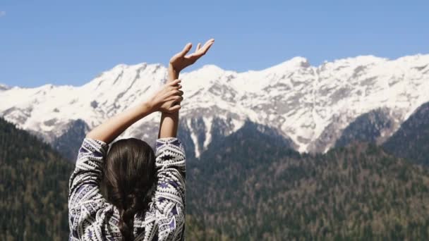 Young woman is looking on amazing mountains with snow caps, stretching hands — Stock Video