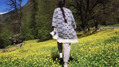 Genç bir kadın yaz aylarında çiçekler geçmiş alanı boyunca yürüyüş