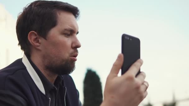 Joven hombre de negocios hablando con su socio de negocios en el teléfono al aire libre durante el día — Vídeos de Stock