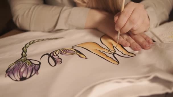 Close up shot of a teenagers hands, who decorates his clothes using watercolor drawing — Stock Video