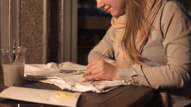 Молода художниця займається малюванням футболки в її маленькій домашній майстерні — стокове відео
