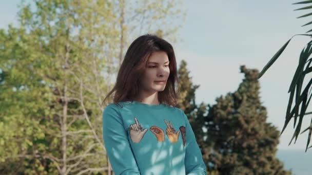 Jonge, mooie vrouw gekleed in een modieuze sweatshirt ballade door het park — Stockvideo