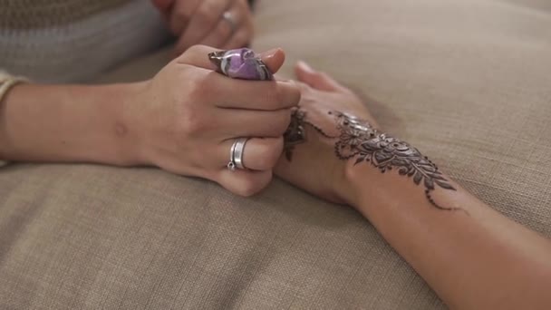 Nahaufnahme einer Frauenhand, die einem Freund ein florales Henna-Muster zeichnet — Stockvideo