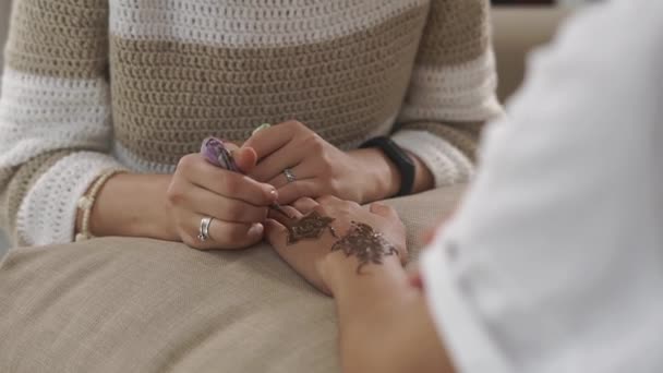 Talented woman is painting female hands by henna mehndi decorations