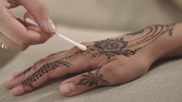 Nahaufnahme einer Frauenhand, der Meister trägt Öl auf das fertige Mehendi auf — Stockvideo