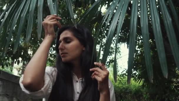 Charming girl posing by the fern. — Stock Video