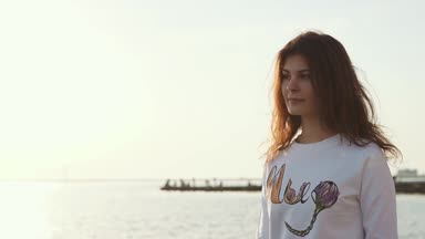 Yalnız büyüleyici kadın dolgu deniz kenarında üzerinde akşam şehirde yürüyor