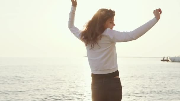 Радостная женщина кружится на морском пляже в лучах солнца — стоковое видео