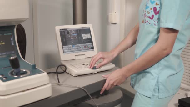 Оптик-женщина корректирует компьютерную программу современного медицинского оборудования — стоковое видео