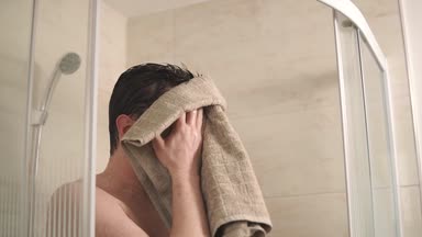 Duştan sonra yüzünü silerek adam.