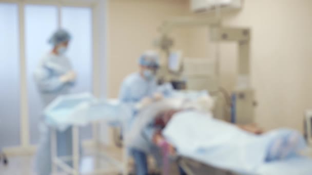 Врачи проводят операцию на пациенте, каркас в дефокусе — стоковое видео