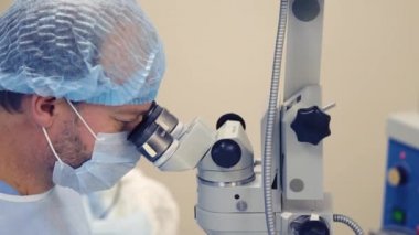 cerrah, mikroskop içinde görünüyor kadeh yukarıya kapatmak ve göz içine bir iğne ekler