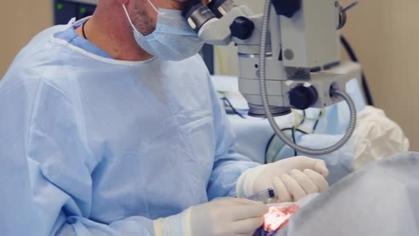 Крупный план рук хирурга со шприцем над человеческим глазом в операционной — стоковое видео