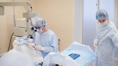 Doktor katarakt tedavisi göz gerçekleştirir, Hemşire göz doktoru yardımcı olur.