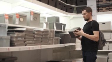 Bir adam süpermarket kutusunda ile raf yakınındaki ayakta ve seçiyor