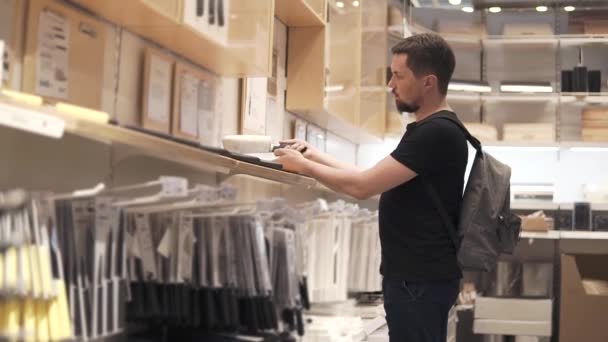 Manliga shopper undersöker köksknivar i en butik i gallerian — Stockvideo