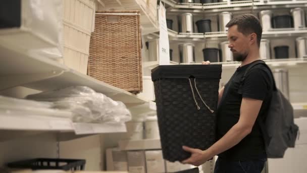 Deportivo hombre está eligiendo cesta de la ropa en una gran tienda — Vídeos de Stock