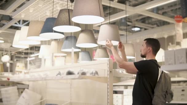 Shopper man está examinando una variedad de pantallas de lámparas en una gran tienda minorista — Vídeos de Stock
