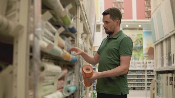 Mestre está comparando dois tipos de papel de parede em uma loja, compras para reparos — Vídeo de Stock