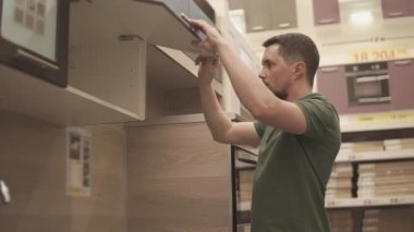 Yetişkin aile reisi bir mobilya mağazasında açılış kapılar mutfak rafları seçmektir