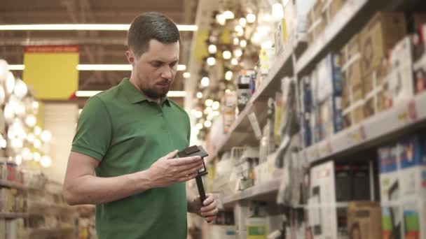 Jovem comprador masculino está segurando lâmpada movida a energia solar na mão na área comercial — Vídeo de Stock