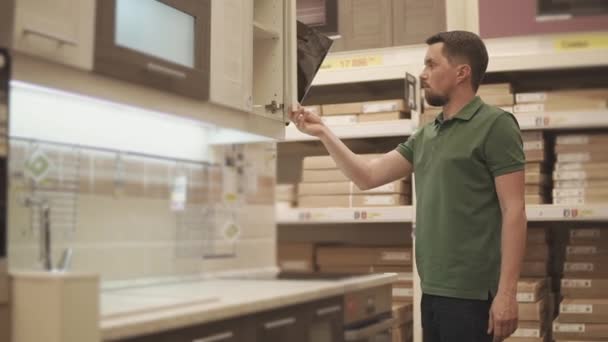 L'homme examine la pièce maîtresse de la cuisine moderne dans un magasin de construction — Video