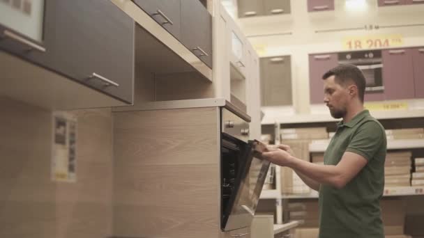 El comprador está inspeccionando el mueble del horno en la cocina de una tienda de muebles — Vídeo de stock