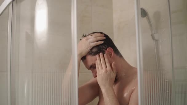 Brunet man is washing head in a shower in home, close-up — Stock Video