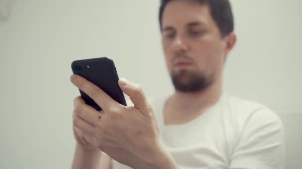 Ver no smartphone preto em mãos masculinas, cara de homem está em segundo plano sem foco — Vídeo de Stock
