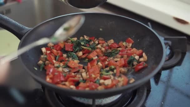 Cook is pouring scrambled eggs in pan with frying vegetables for cooking omelet — Stock Video