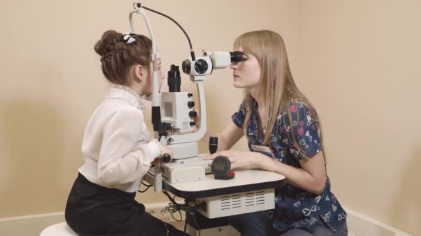 Врач занимается биомикроскопией глаза, проверяет глаза на наличие заболеваний — стоковое видео