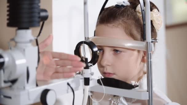 Врач занимается биомикроскопией глаза, он проверяет глаза подростка — стоковое видео