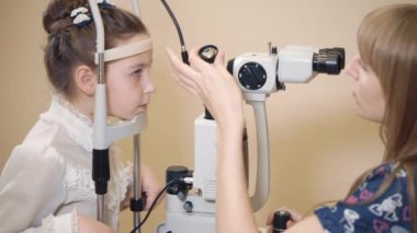 Kadın göz doktoruna biomicroscopy aparatı yakınındaki küçük kız başkanı Düzeltme