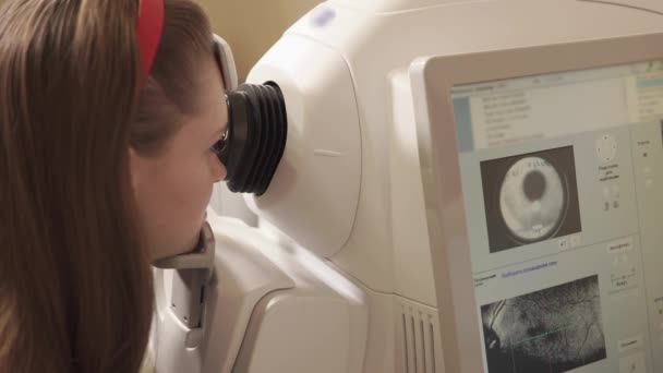 Vrouw zit voor tomografie toestellen in oogheelkundige kliniek — Stockvideo