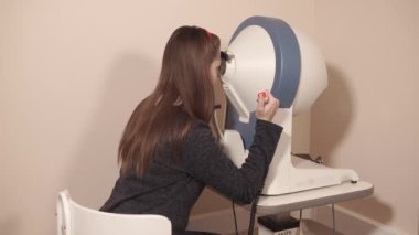 Kız içinde seyir ve tuşuna basarak bir bilgisayar perimetry üzerinde oturuyor