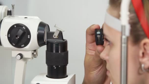 Chica está sentado tranquilamente durante la biomicroscopia de la encuesta de los ojos — Vídeos de Stock