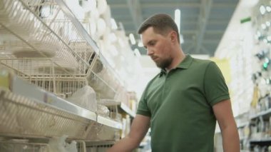 Genç bir adam raflarda bir alışveriş merkezinde bir sokak lambası inceliyor.