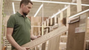 adam alışveriş merkezinde laminat zemin inceliyor, o dairede tamirat yapar