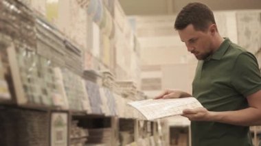 Genç bir adam elinde Branda için bir kiremit tutar, mağazaya