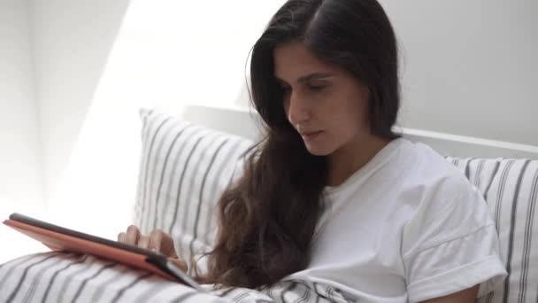 Young woman reading a book on a modern portable tablet and smiling — Stock Video