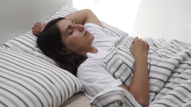 Jovem mulher jaz na cama com os olhos fechados, senhora está dormindo — Vídeo de Stock