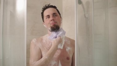 kullanan bir sabunlu bez için duş banyo banyoda suyun altında yıkayın için genç ve yakışıklı bir adam portresi.