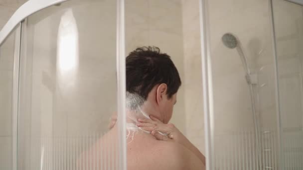 A man lathers his neck and hair with shampoo in order to be clean — Stock Video