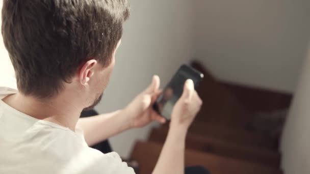 Een jongeman maakt gebruik van een mobiele telefoon en het Internet om online dingen te kopen — Stockvideo