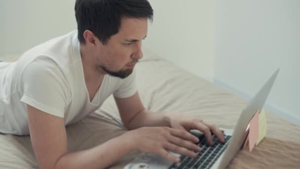 Egy fiatal férfi, pihenő előtt a laptop, ül a szociális hálózatok — Stock videók